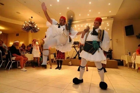 2 men dancing a traditional Greek dance with uniforms