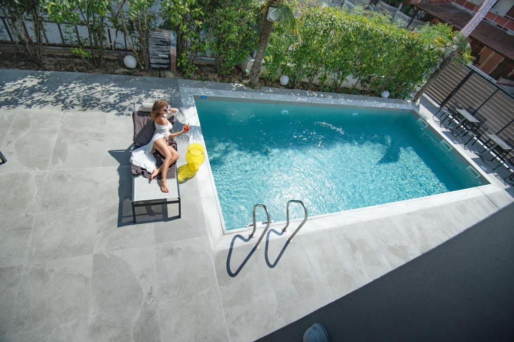 Pool with a deck chair with a woman sitting on it 